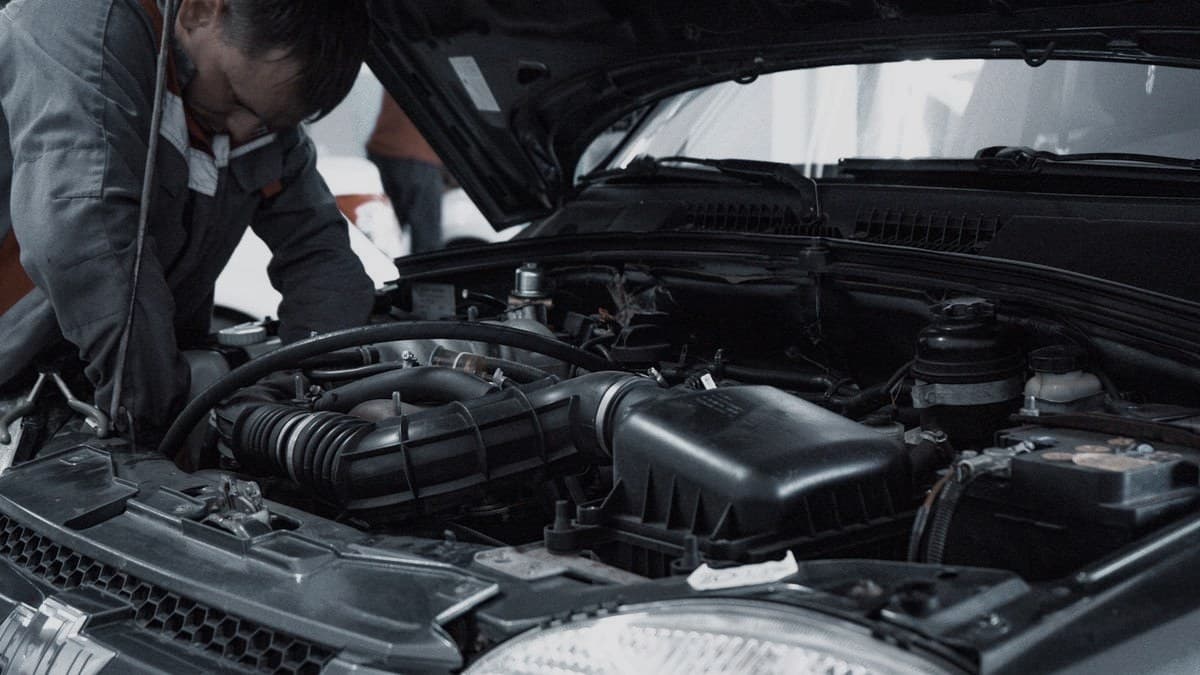 A mechanic inspecting a car engine under an open hood