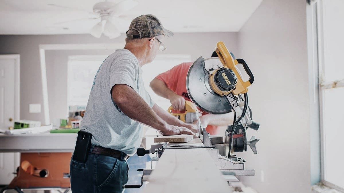 A contractor cutting wood with a miter saw during a home renovation
